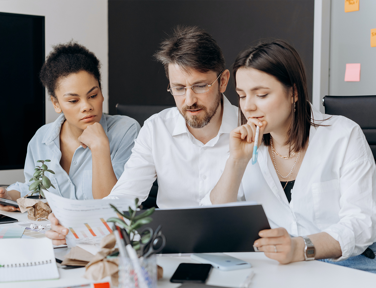 Three people are sitting at a table looking at something on the computer.