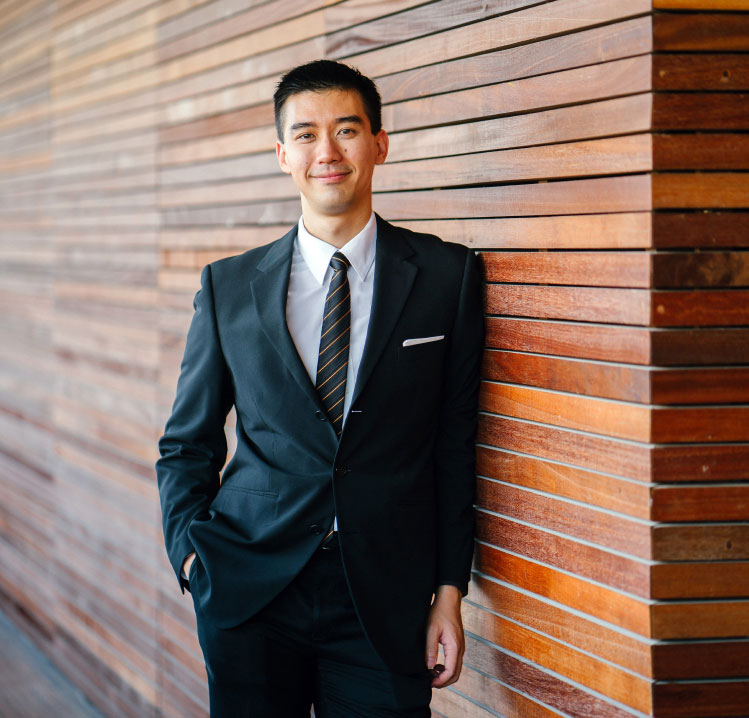 Man smirking A man in suit and tie leaning against a wall.