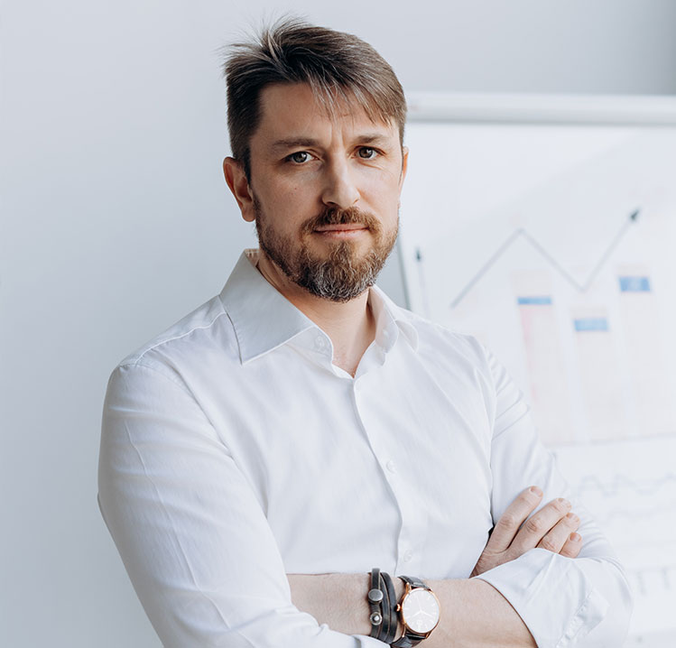 Serious man A man with beard and white shirt standing in front of wall.